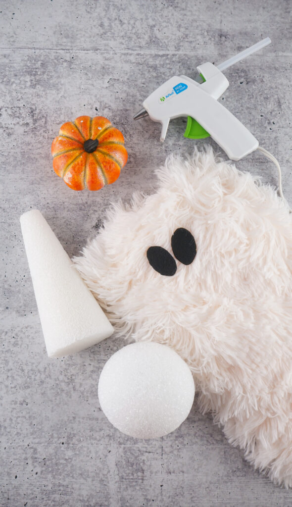 Viral Sherpa Ghost DIY Halloween craft made with fluffy white sherpa fabric, black felt eyes, and a small orange pumpkin.