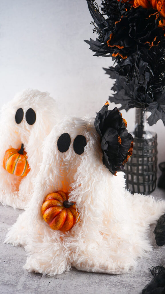 Viral Sherpa Ghost DIY Halloween craft made with fluffy white sherpa fabric, black felt eyes, and a small orange pumpkin.