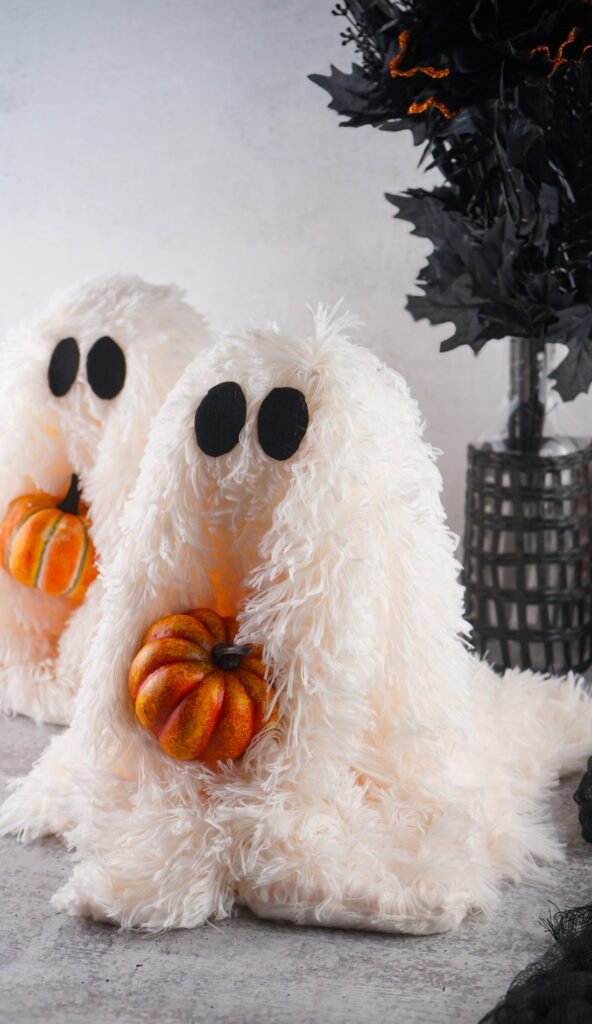Viral Sherpa Ghost DIY Halloween craft made with fluffy white sherpa fabric, black felt eyes, and a small orange pumpkin.