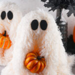 Viral Sherpa Ghost DIY Halloween craft made with fluffy white sherpa fabric, black felt eyes, and a small orange pumpkin.