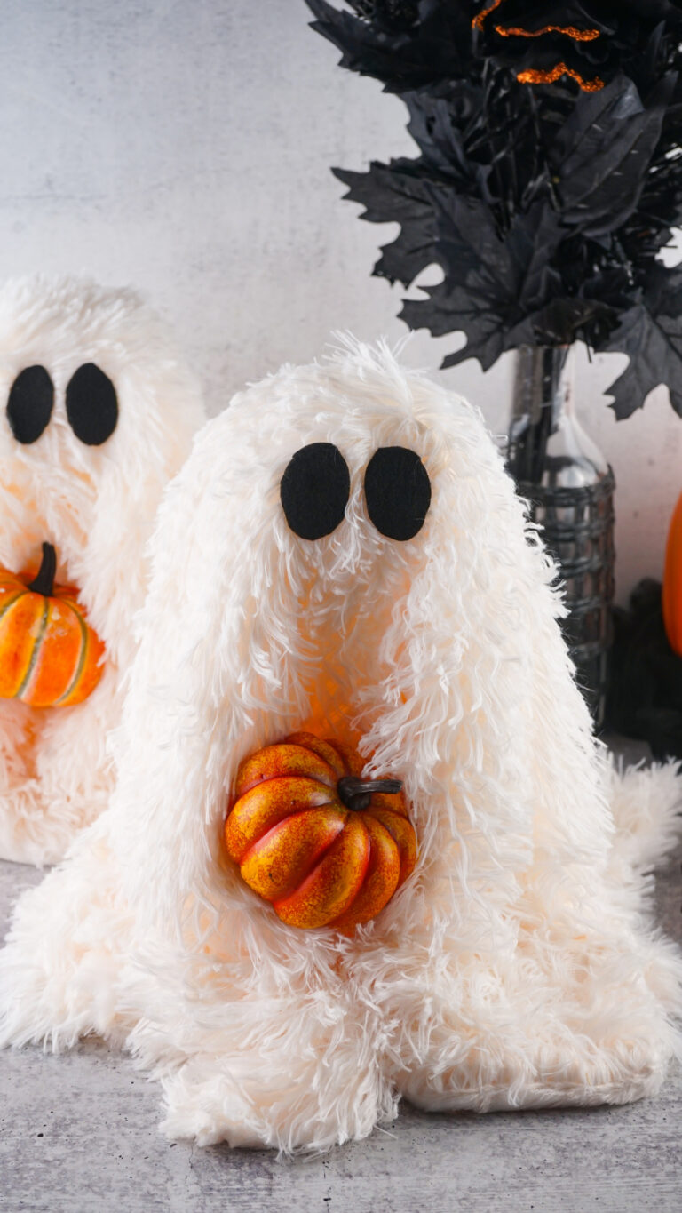 Viral Sherpa Ghost DIY Halloween craft made with fluffy white sherpa fabric, black felt eyes, and a small orange pumpkin.