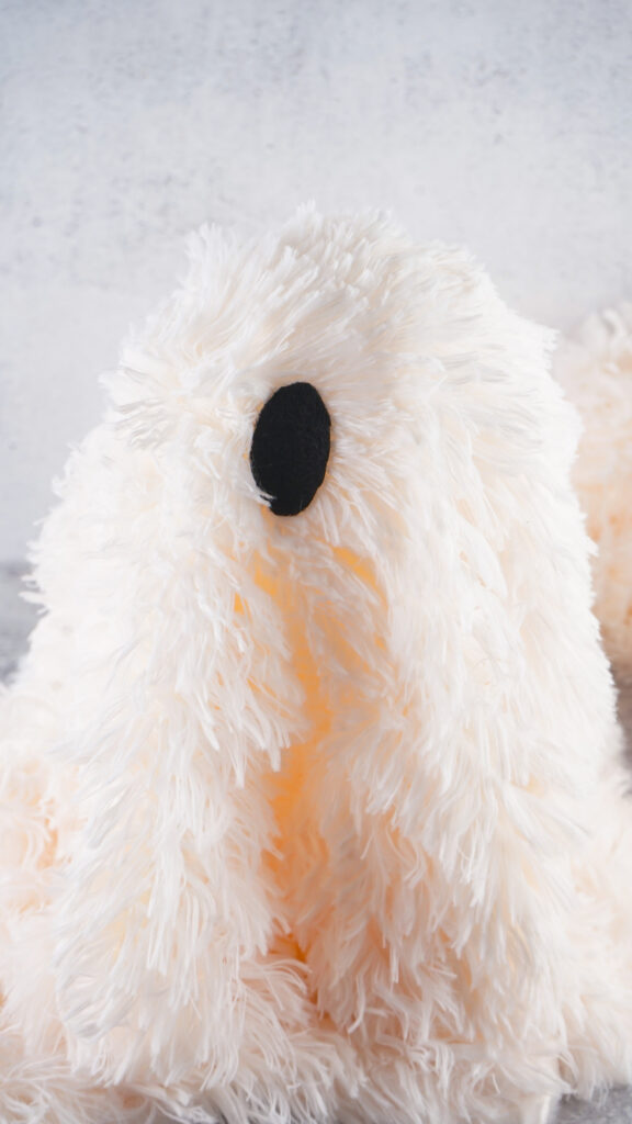 Viral Sherpa Ghost DIY Halloween craft made with fluffy white sherpa fabric, black felt eyes, and a small orange pumpkin.