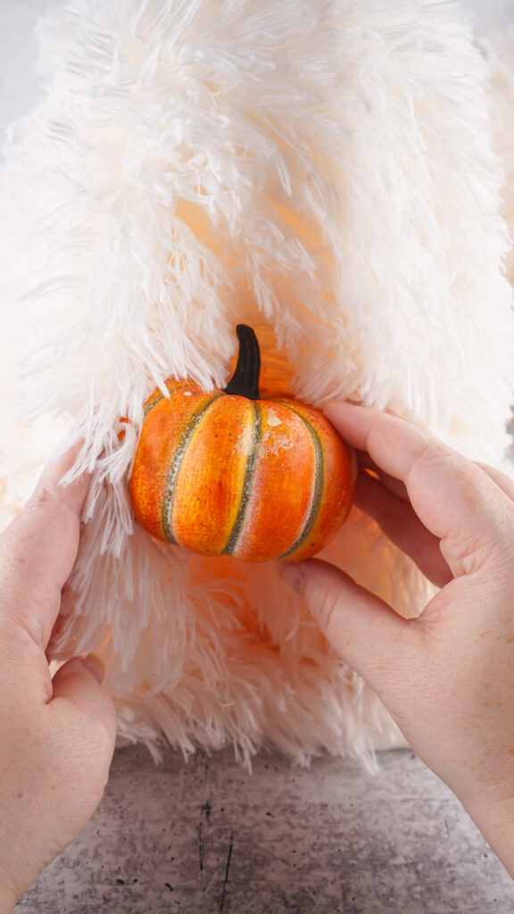 Viral Sherpa Ghost DIY Halloween craft made with fluffy white sherpa fabric, black felt eyes, and a small orange pumpkin.