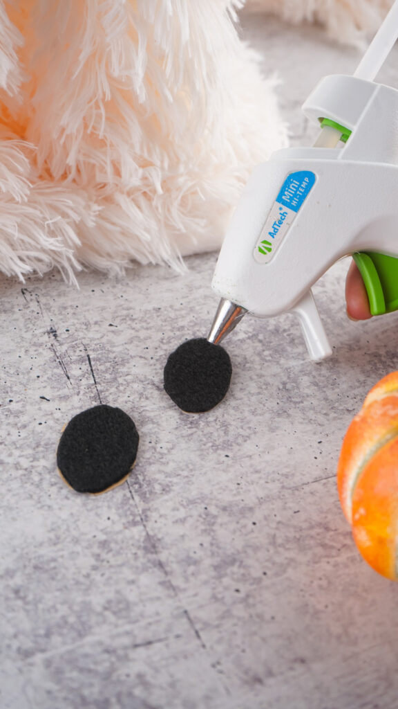 Viral Sherpa Ghost DIY Halloween craft made with fluffy white sherpa fabric, black felt eyes, and a small orange pumpkin.
