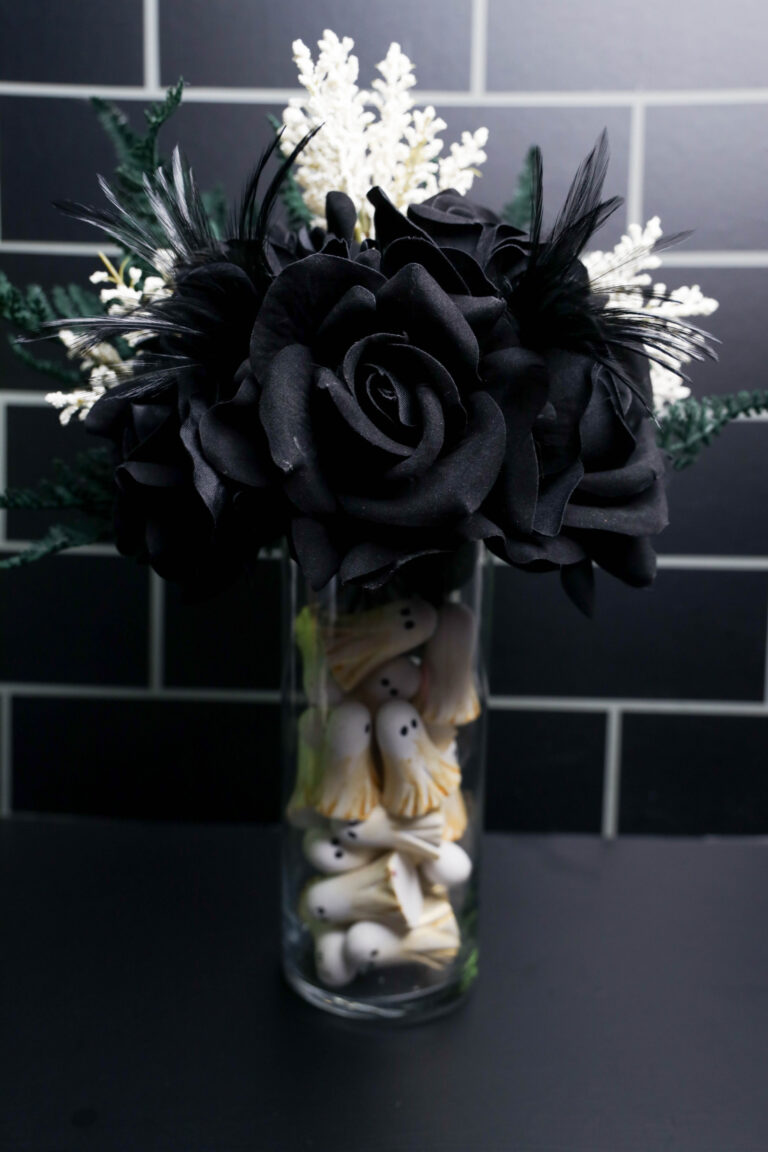 This DIY Ghost Vase combines tiny white ghosts, black velvet roses, feathers, greenery, and white florals for an easy Halloween centerpiece.